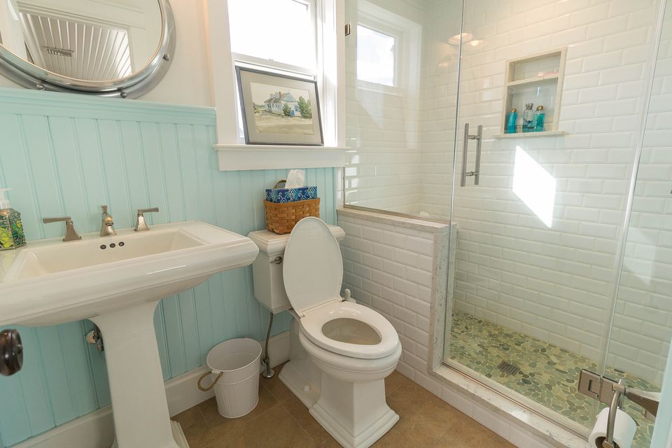 Bath with aqua beadboard, a pedestal sink, and a tiled shower