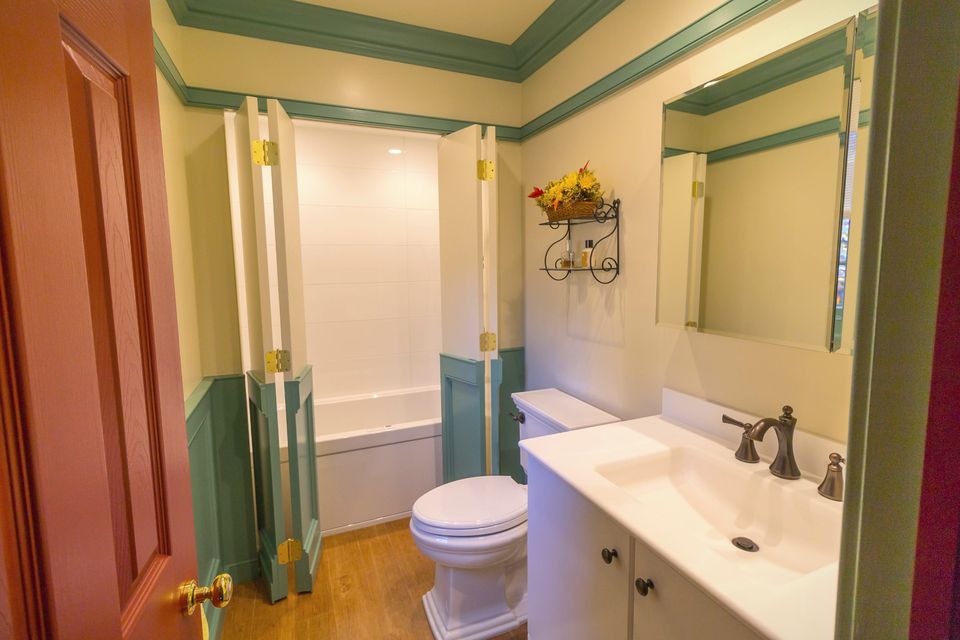 Bath with green painted trim and a white vanity