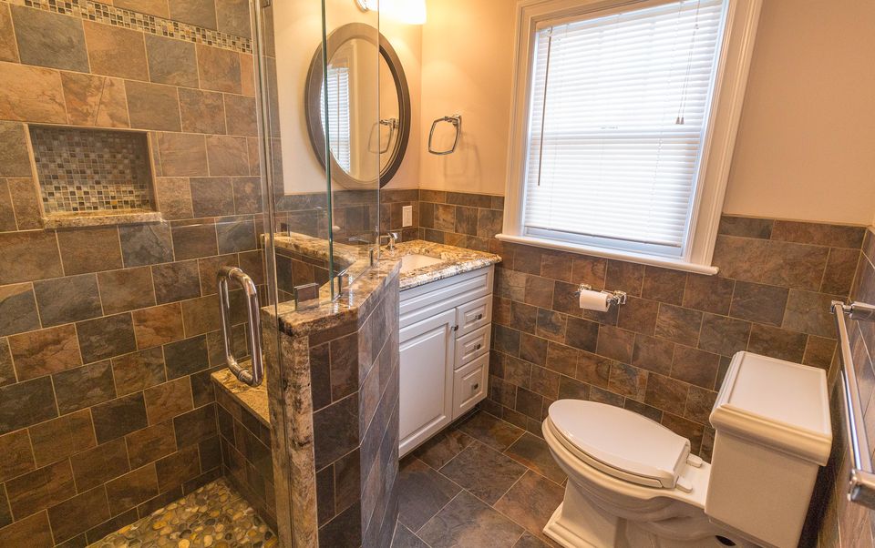 Bath with slate tile walls, a shower niche, and a pebble floor