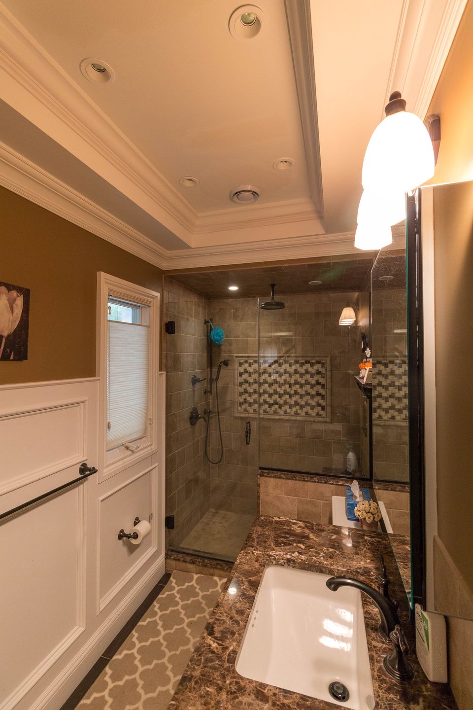 Bath with a tiled glass shower and a white vanity