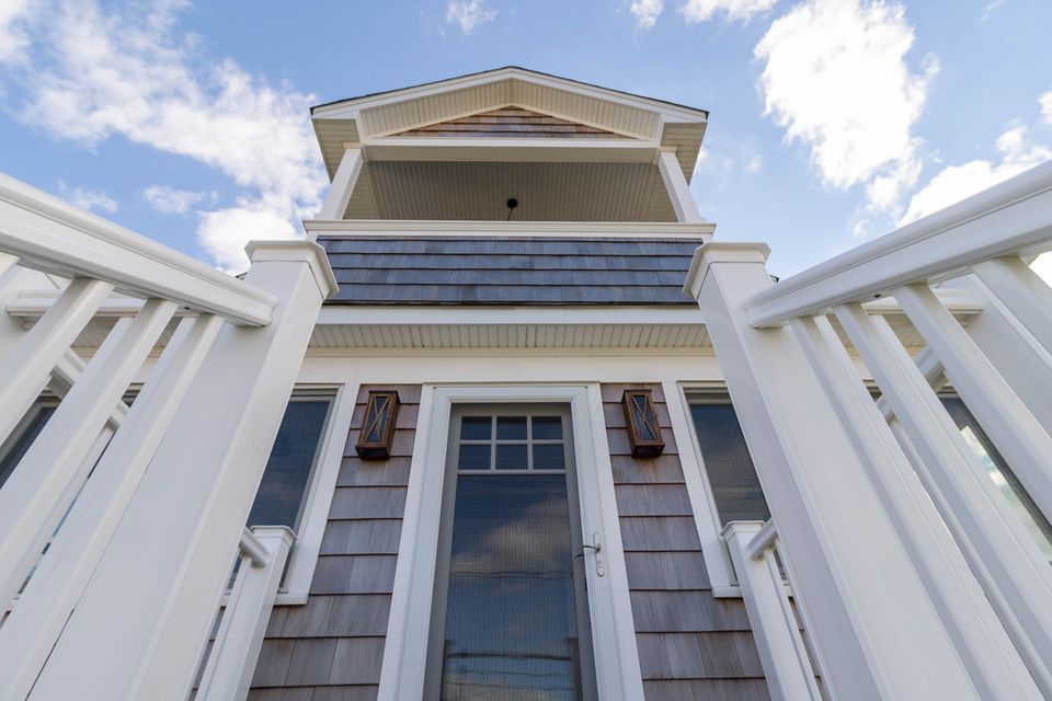 Beach house facade seen from below, with balconies and white rails