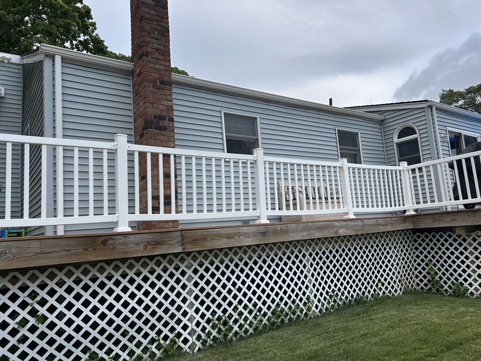 Raised deck with white rails and lattice skirting along blue siding