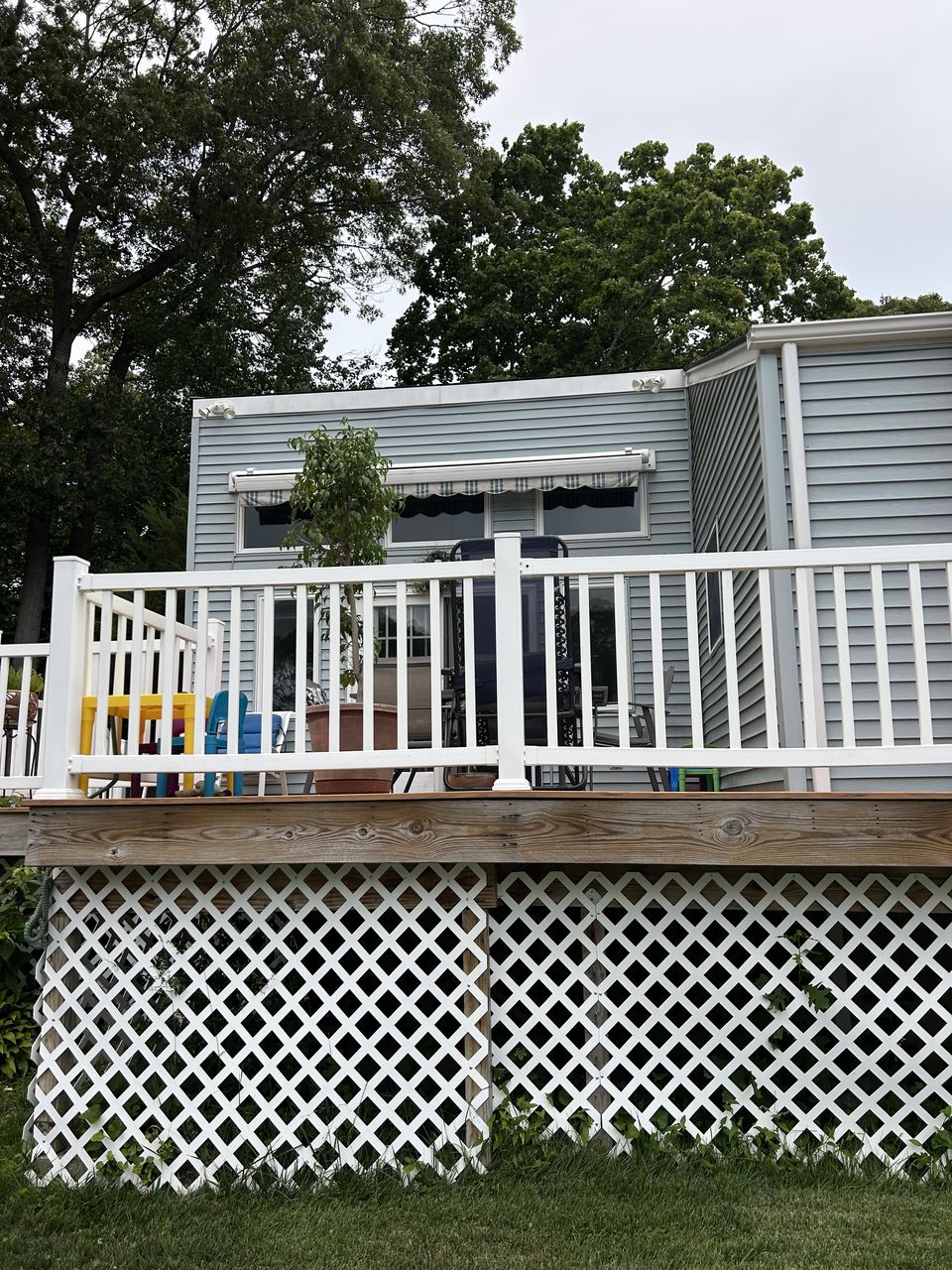 Raised deck with white rails and lattice skirting, seen from the yard