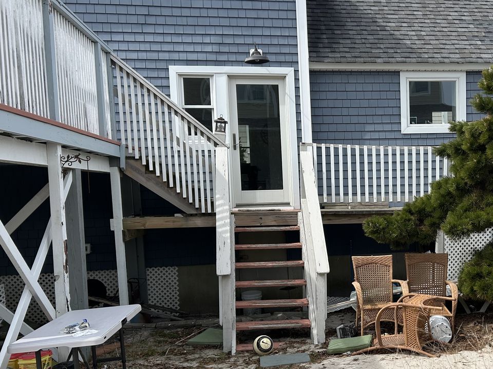 Before: worn wood stairs to the back door beside an open deck, with clutter underneath