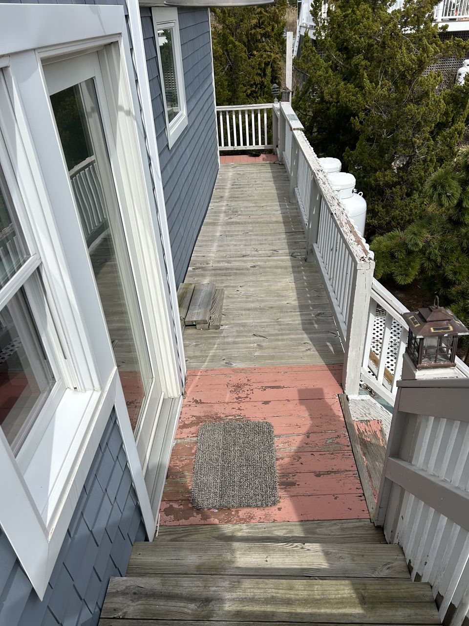 Before: worn wood walkway with painted boards along the side of the house