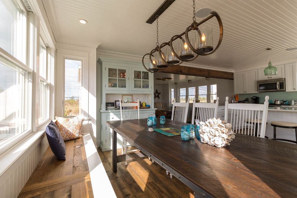 Open dining room and kitchen with a long wood table and iron chandelier