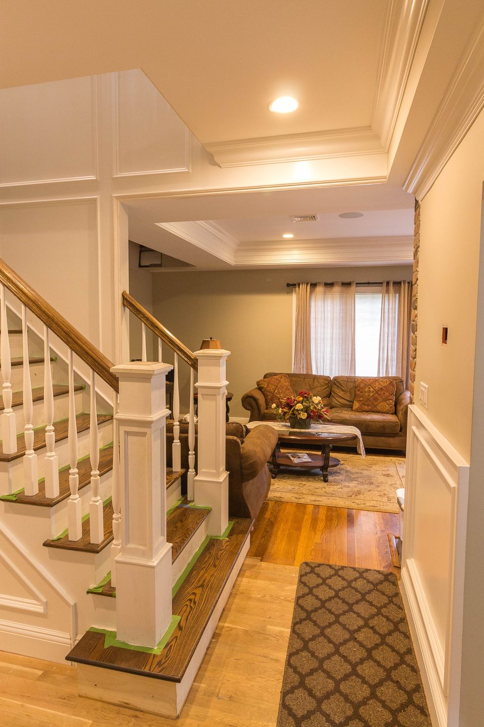 Foyer staircase with white balusters and a wood rail