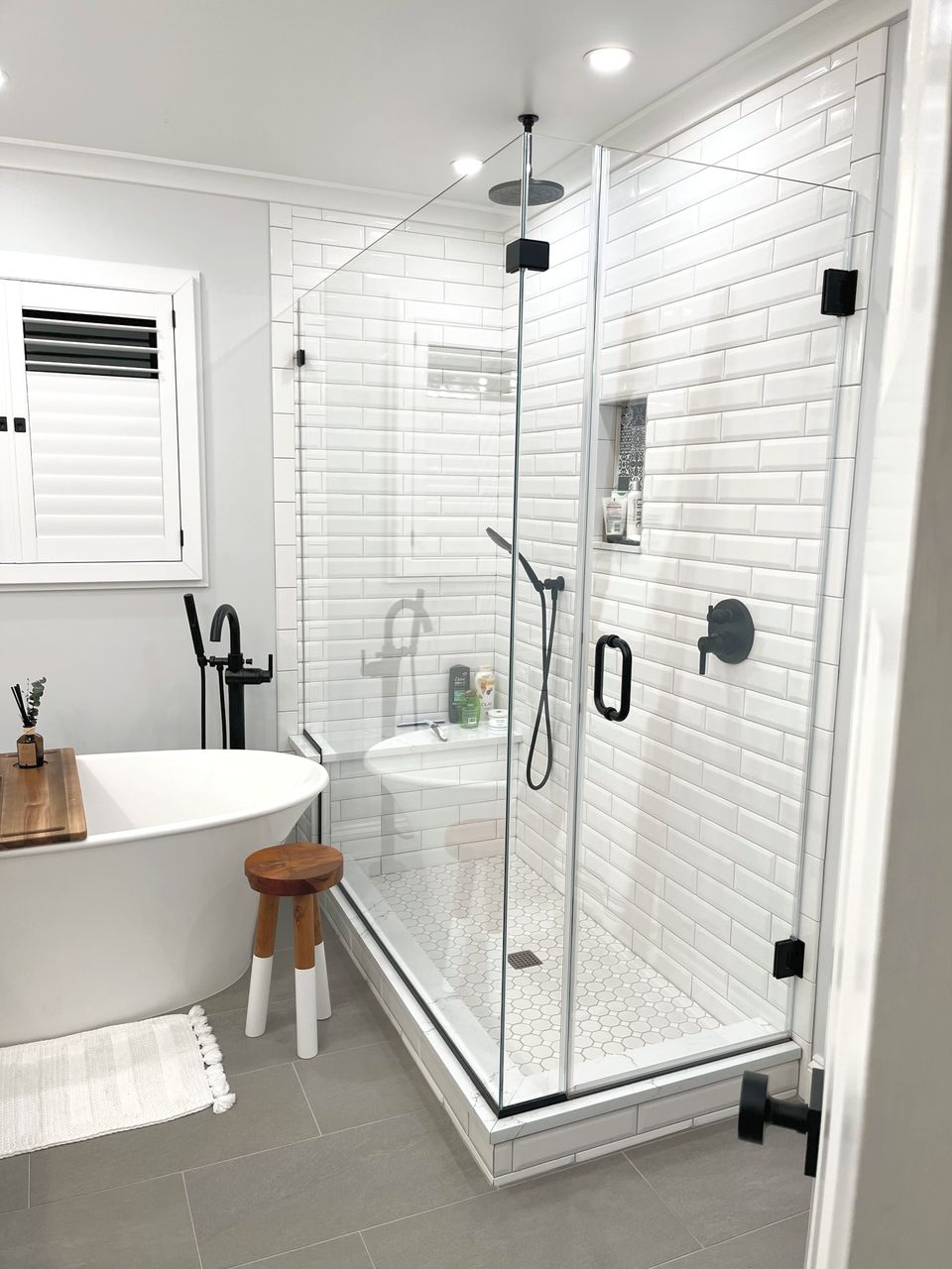 Frameless glass shower beside a freestanding tub