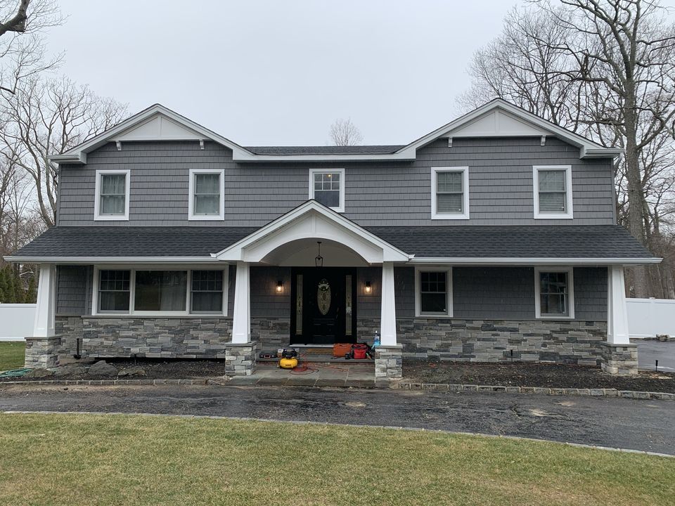 Dark gray colonial with a front portico and stone base