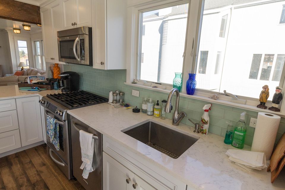 Kitchen with a gas range, aqua glass tile backsplash, and quartz counters