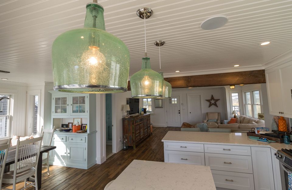 Open kitchen with green glass pendants under a beadboard ceiling