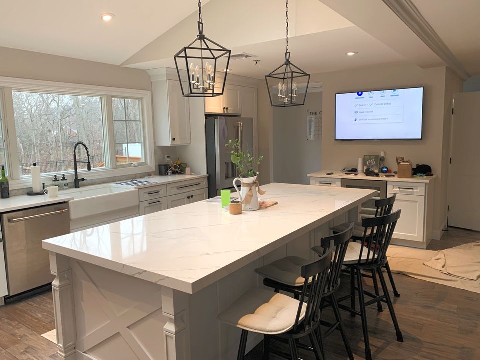 Kitchen with a large quartz island, black lantern pendants, and white cabinets