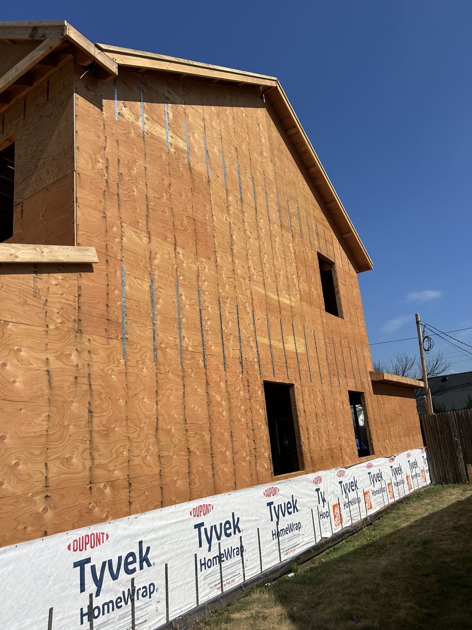 Sheathed gable wall of a new build, with house wrap along the foundation