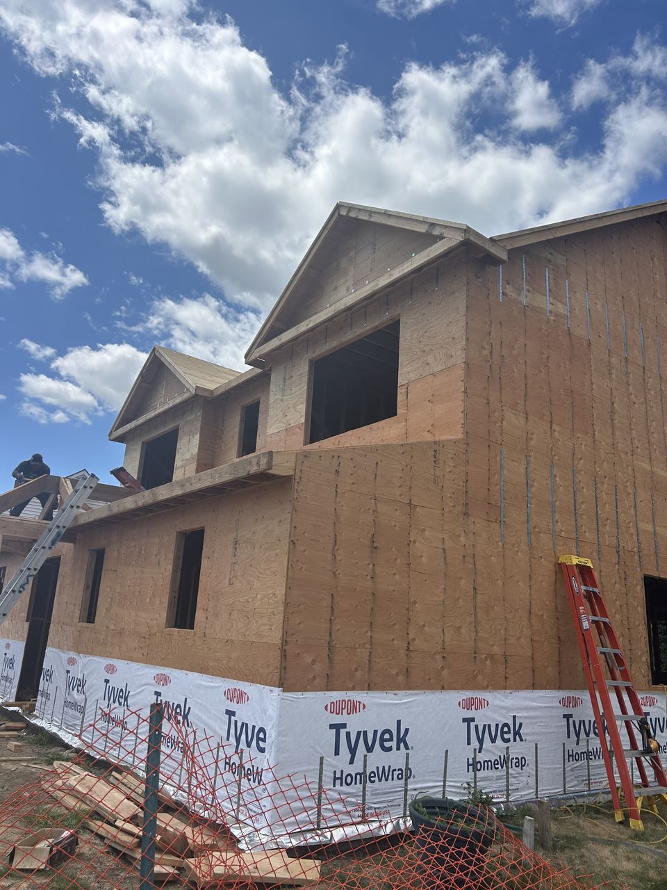 New build with sheathed gables and window openings under a blue sky