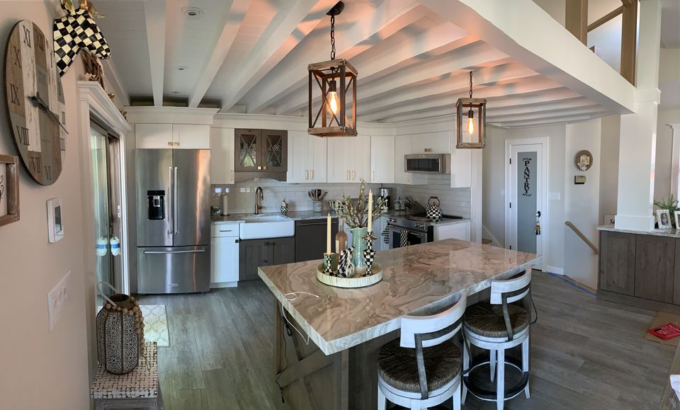 Open kitchen with painted ceiling beams, lantern pendants, and an island