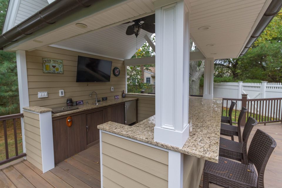 Outdoor kitchen cabana with a granite bar and TV