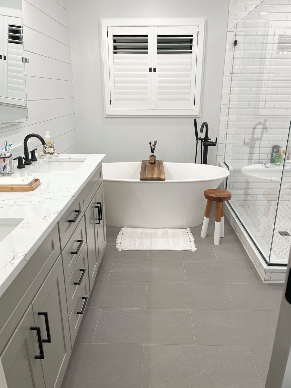Primary bath with a freestanding tub, glass shower, and gray vanity
