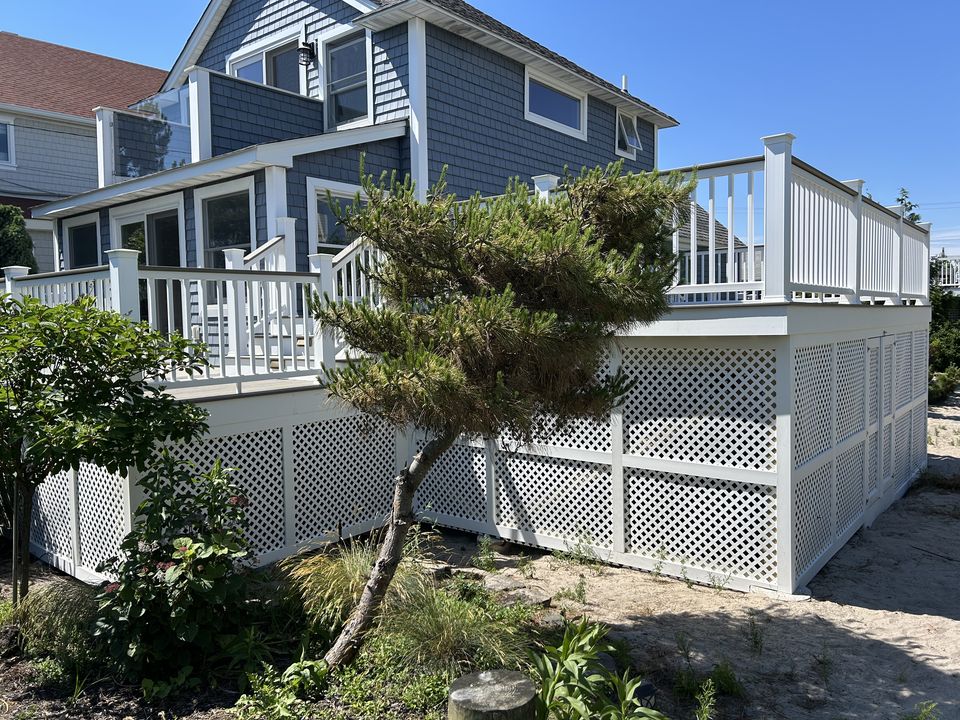 Raised deck with lattice skirting wrapping the back of a shingle house