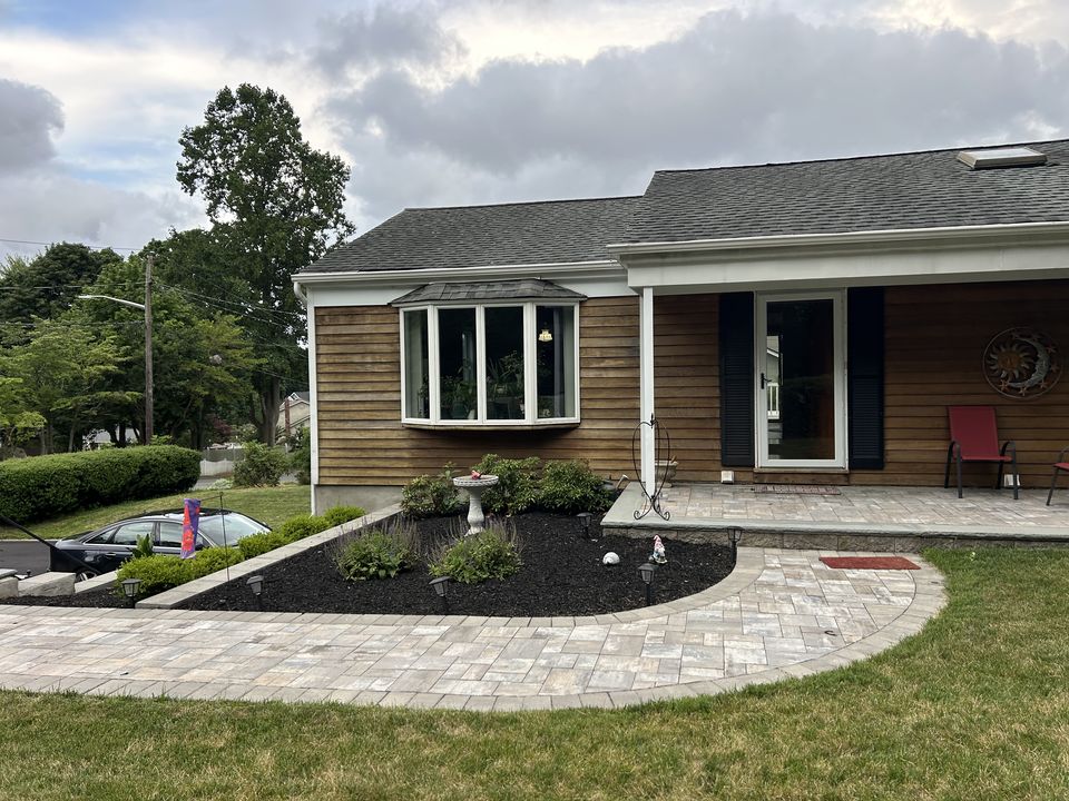 Curved paver walk and planting bed in front of a cedar sided ranch