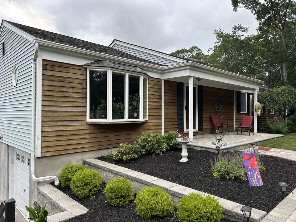 Cedar sided ranch with a new paver walk, a raised planting bed, and shrubs