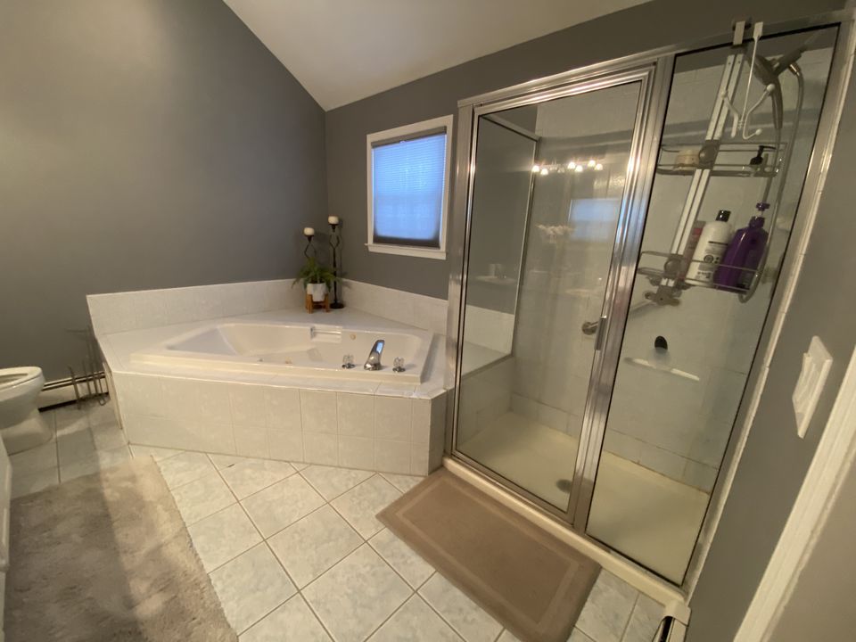 Before: corner tub and a framed glass shower