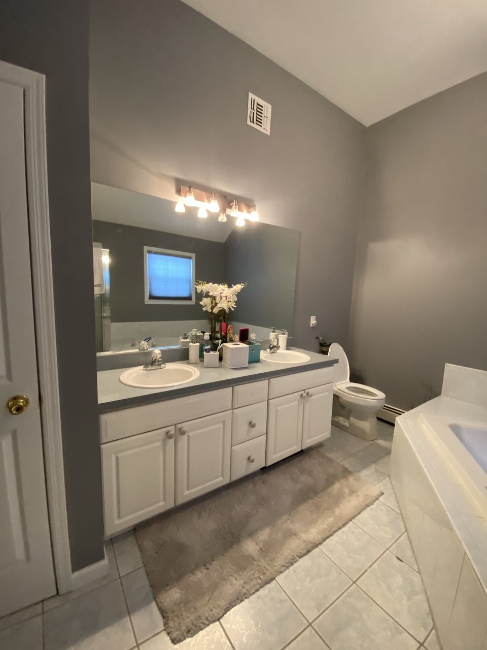 Before: primary bath with a double vanity, gray walls, and a tile floor
