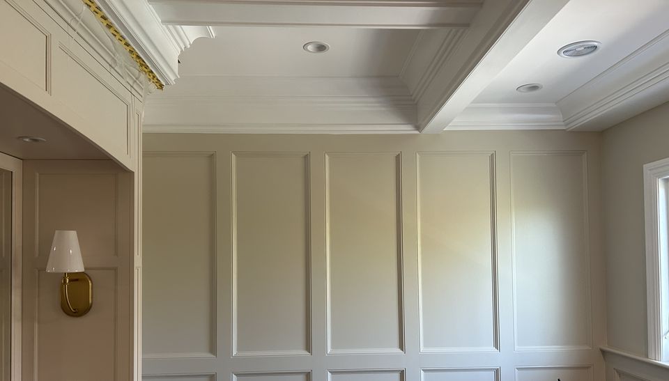Paneled walls and a brass sconce under the coffered ceiling