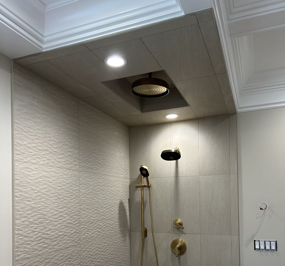 Shower wall in textured tile with a brass hand shower and valve