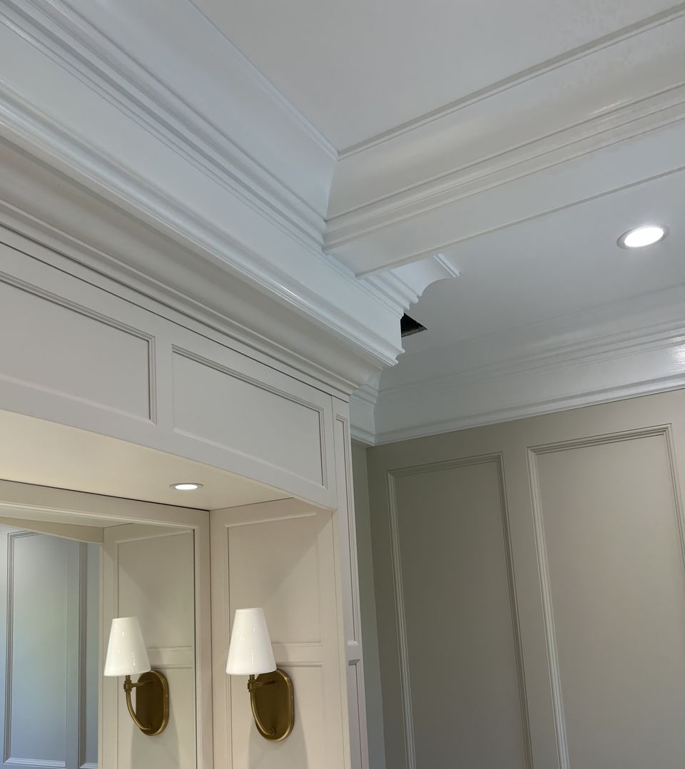 Vanity mirror framed in paneling, with brass sconces