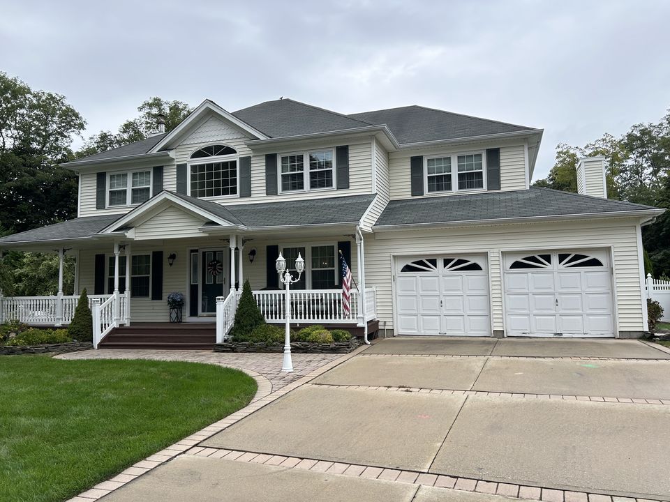 Before: white vinyl colonial with a farmer's porch and a two car garage