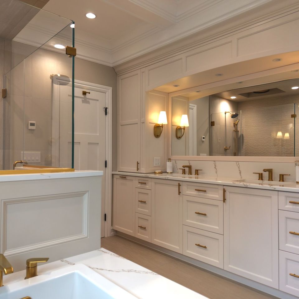 Double vanity with brass hardware and sconces, a framed mirror, and paneled walls