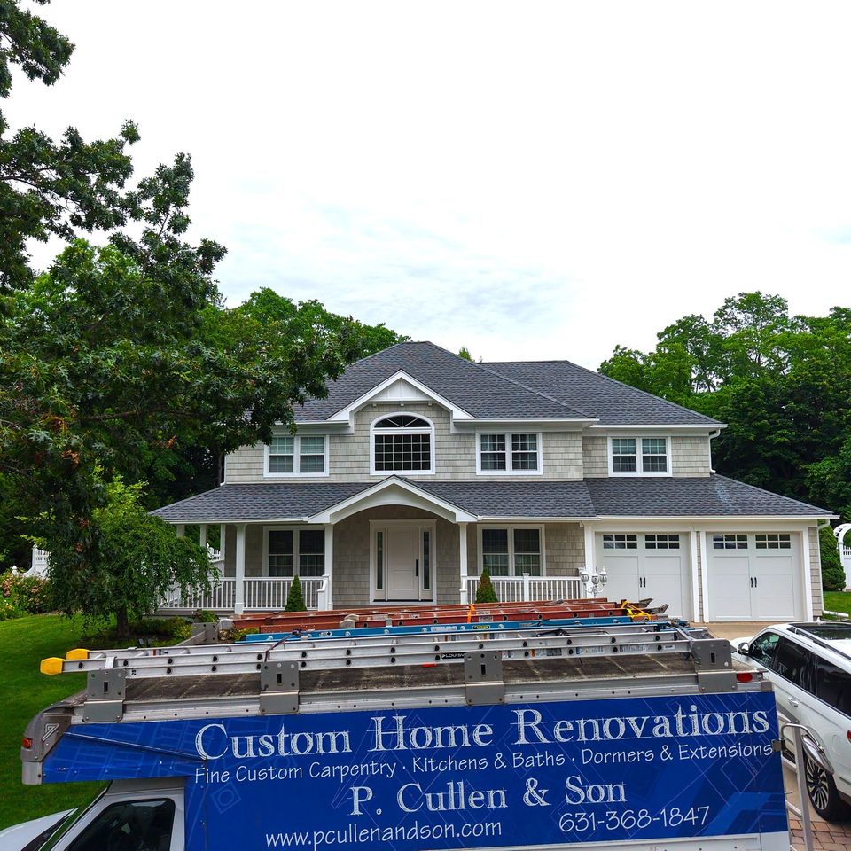 The finished front from the air: cedar shake, a new portico with an arched window above, and the P. Cullen and Son truck in the drive