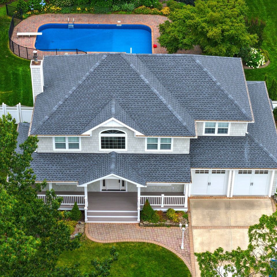The finished house from above: cedar shake, the new portico and porch, the two car garage, and the pool behind it
