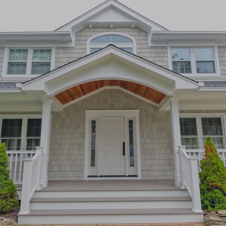 The finished front portico with a wood ceiling, square columns, white rails, and new steps