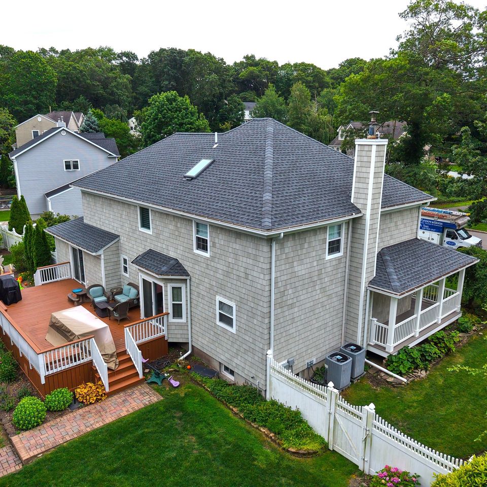 The finished rear from the air, in cedar shake with the deck and the covered porch