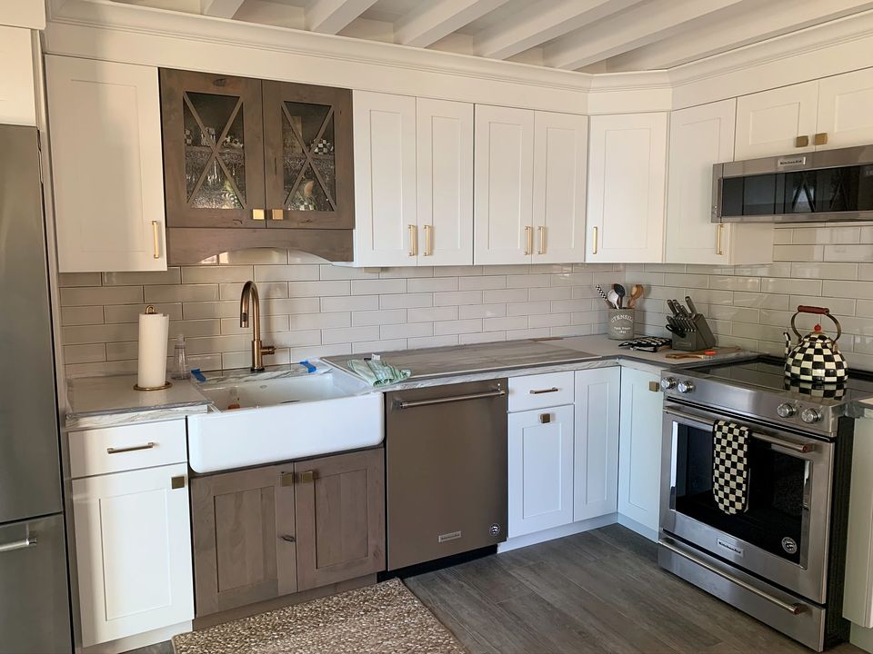 White shaker kitchen with a farmhouse sink, subway tile, and glass front upper cabinets